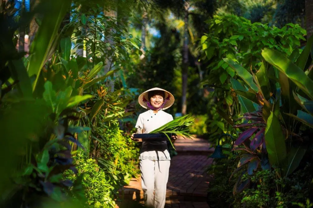 Discerning global travelers unwinding inside elegant treatment rooms wrapped in tropical gardens.