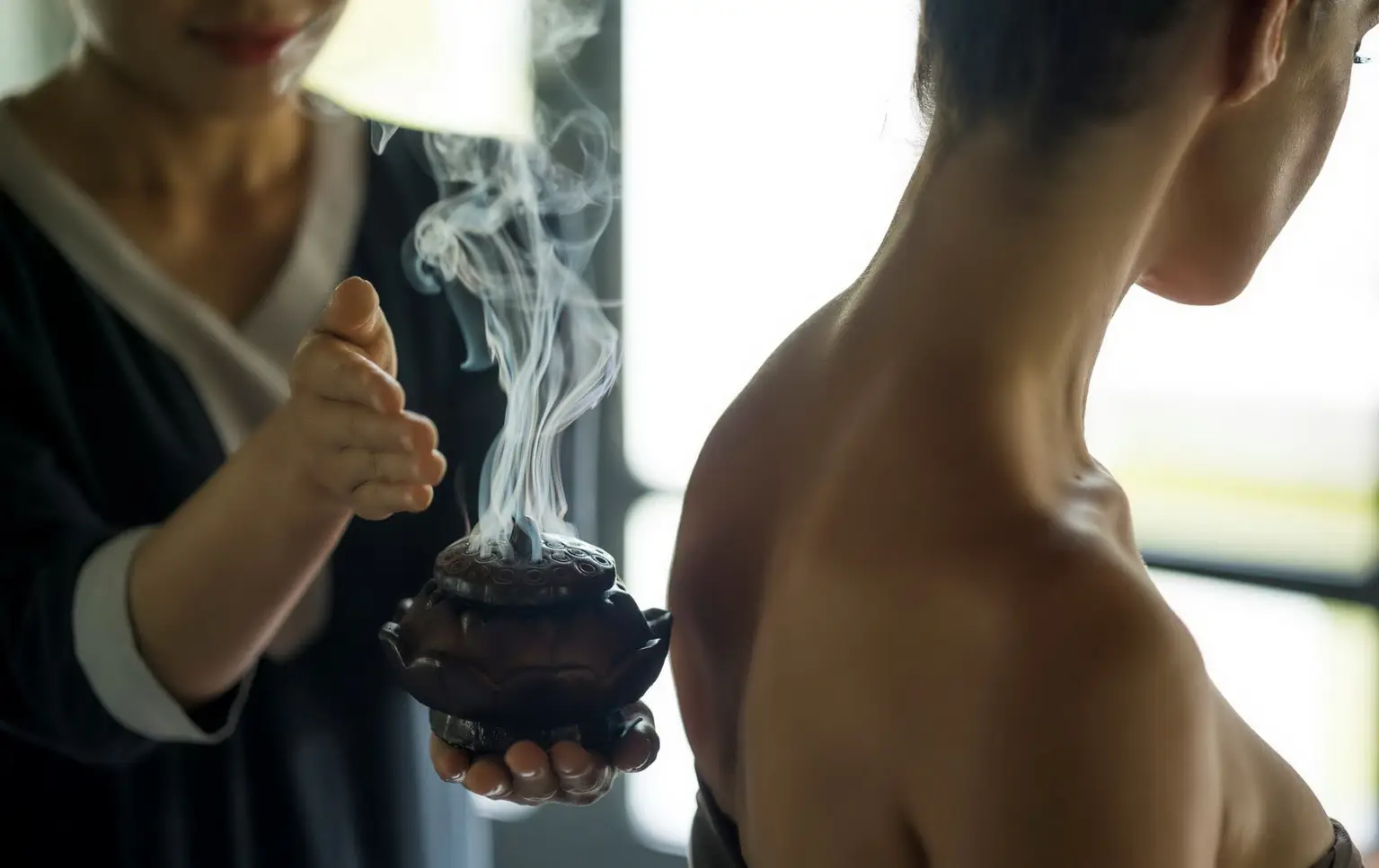 An international traveler experiencing a smoke purification healing session in a serene, open-air garden.  